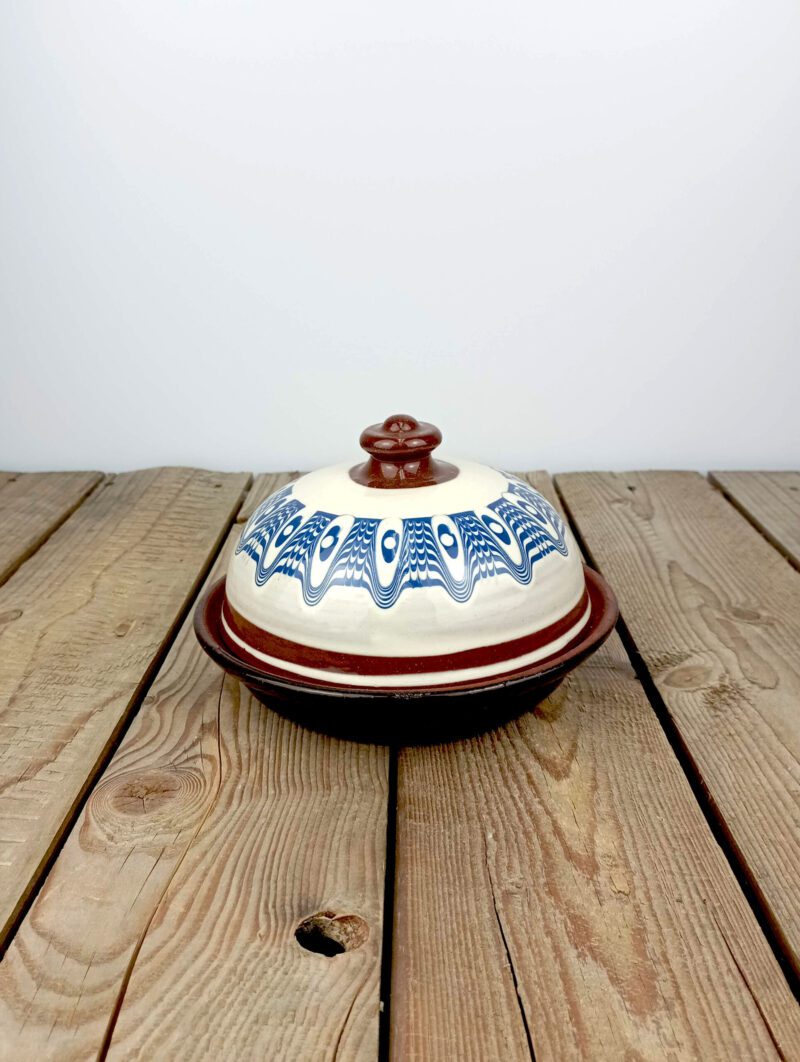 Obrazek przedstawia: bułgarska biała maselniczka ceramiczna, z niebieskim wzorem. Oryginalna bułgarska ceramika, ręczna robota.