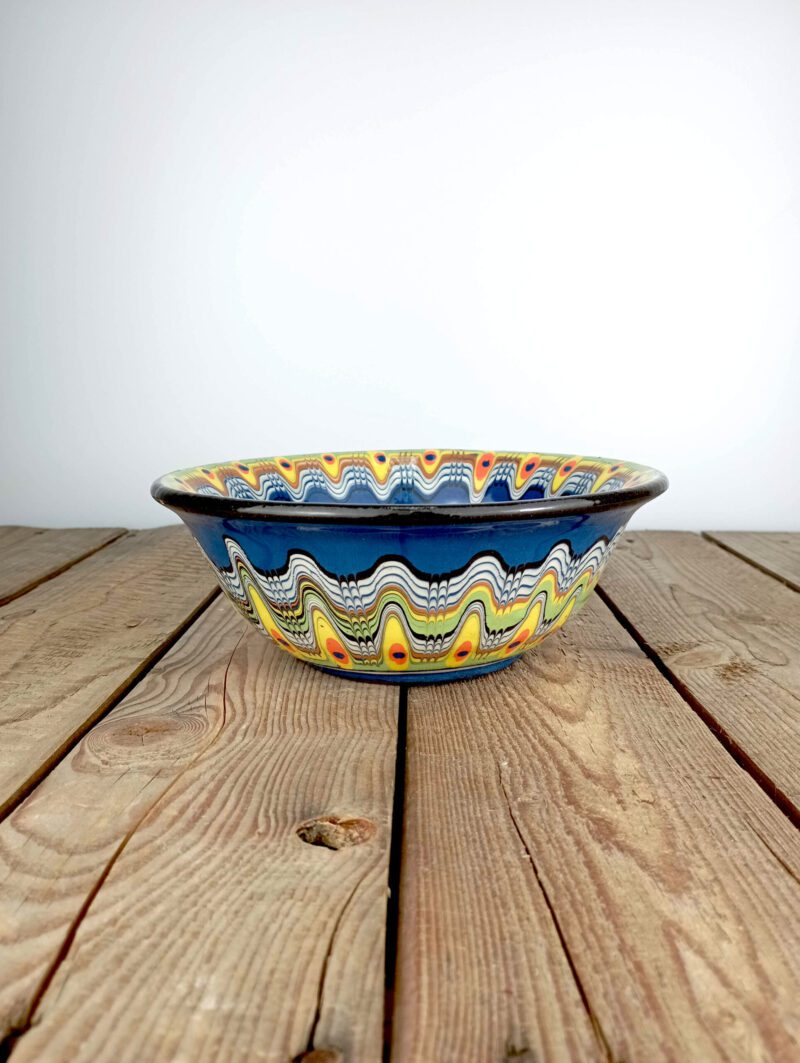 Obrazek przedstawia z boku: bułgarska gliniana miska obiadowa - o średnicy ok. 20cm i pojemności ok. 0,95l. Niebieska z wielokolorowym ludowym wzorem. Oryginalna ceramika bułgarska, produkt ręcznie wykonany i malowany.