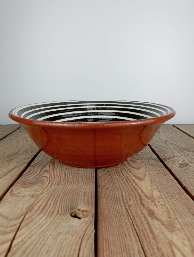 Obrazek przedstawia: bułgarska gliniana czarna miska duża - o średnicy ok. 25cm i pojemności ok. 1,75l, ze wzorem białej spirali. Oryginalna ceramika bułgarska, produkt ręcznie wykonany i malowany.