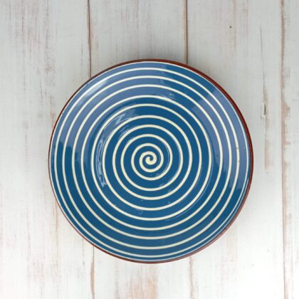 Obrazek przedstawia: bułgarski gliniany talerz płaski obiadowy, niebieski z białym wzorem spirali, o średnicy ok. 26cm. Oryginalna ceramika bułgarska, talerz ręcznie wykonany i malowany.